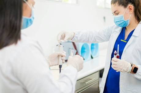 Two student nurses working in a lab environment holding test tubes